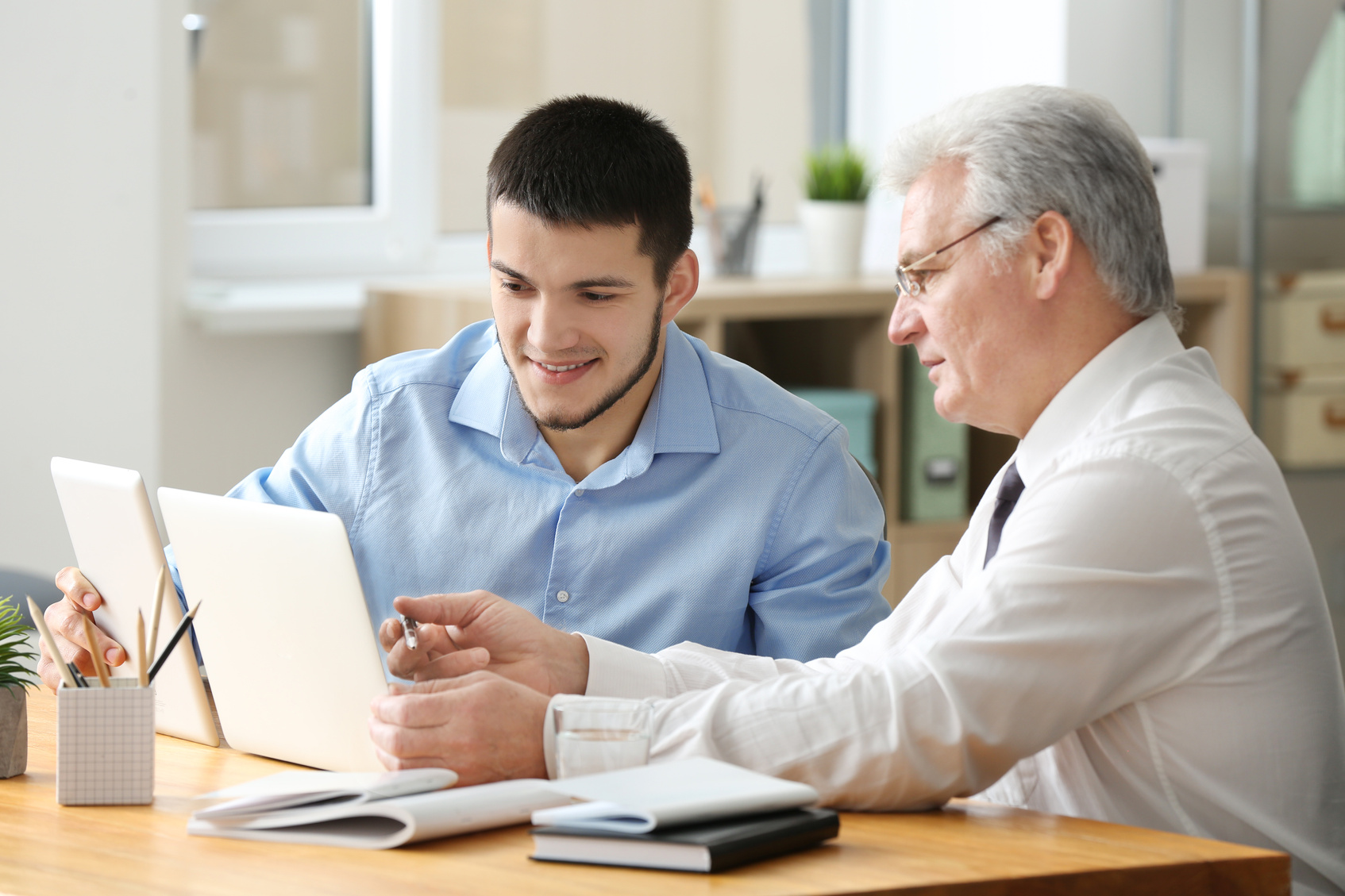 Mature Marketing Manager with Young Male Trainee Working in Office